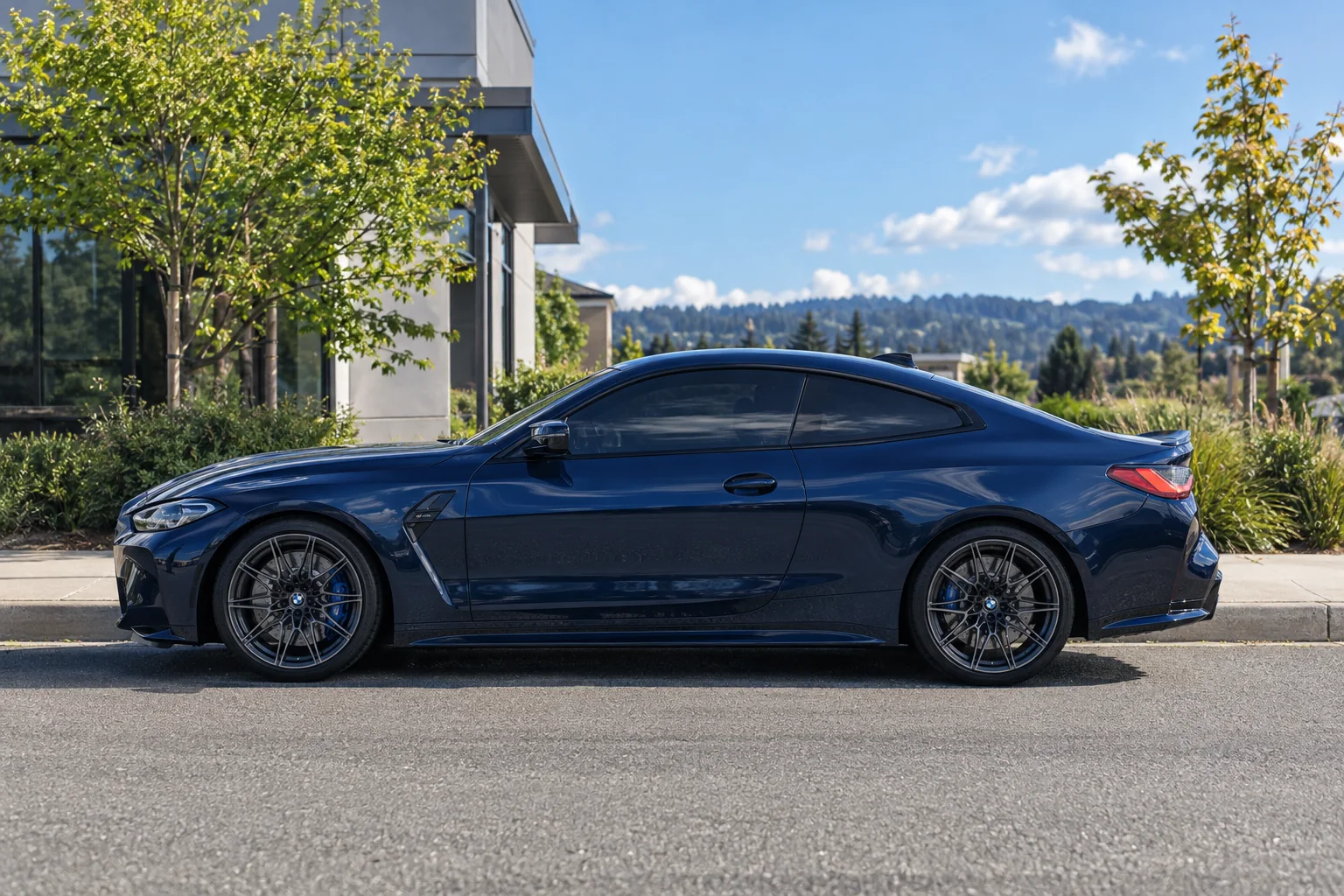 A blue BMW M4 with tinted windows parked on a street