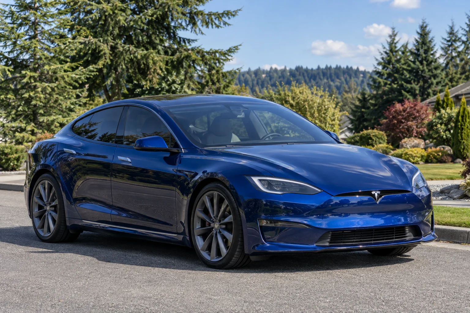 A blue Tesla Model S with tinted windows on a quiet street